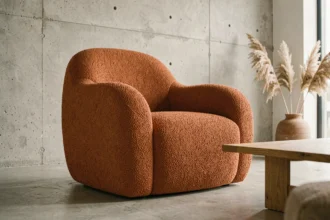 Fauteuil design scandinave en tissu bouclé terracotta dans un salon minimaliste aux murs en béton brut