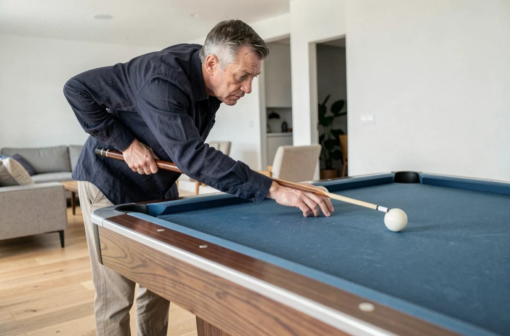 Joueur de billard adulte concentré sur une table Chevillotte contemporaine dans un salon moderne au parquet clair