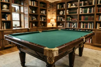 Table de billard Chevillotte en noyer massif avec tapis vert dans une salle de jeu élégante aux murs en brique apparente